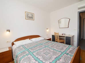A bedroom with a bed, a desk, a chair, a mirror, and a wall-mounted picture. - Quiet and Compact Apartment With Balcony (Rovinj)