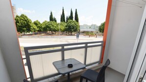 A balcony with a table and two chairs, a view of trees and a building in the background. - Quiet and Compact Apartment With Balcony (Rovinj)