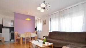 A living room with a brown sofa, wooden chairs, a table, and a purple wall. - Quiet and Compact Apartment With Balcony (Rovinj)