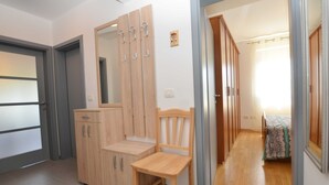 A room with a wooden wardrobe, a mirror, a wooden chair, and a bed with a patterned bedspread. - Quiet and Compact Apartment With Balcony (Rovinj)