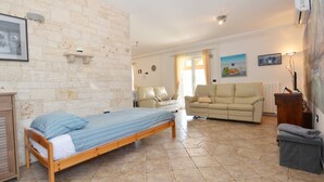Un dormitorio con cama, sofá, una mesita y una silla.
