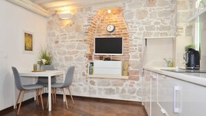 Una cucina moderna con parete in pietra, televisore a schermo piatto, zona pranzo con due sedie e macchina da caffè.