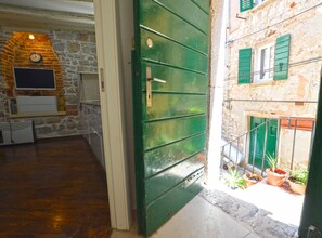 Leading to a cozy retreat with a green door, this corridor offers a glimpse into a charming room with a balcony and exposed brick walls.