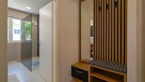 A modern bedroom with a glass door leading to a balcony, a wooden vanity with a mirror, and a small wooden bench. - Modern and Stylish Rovinj Apartments With Terrace (Rovinj)