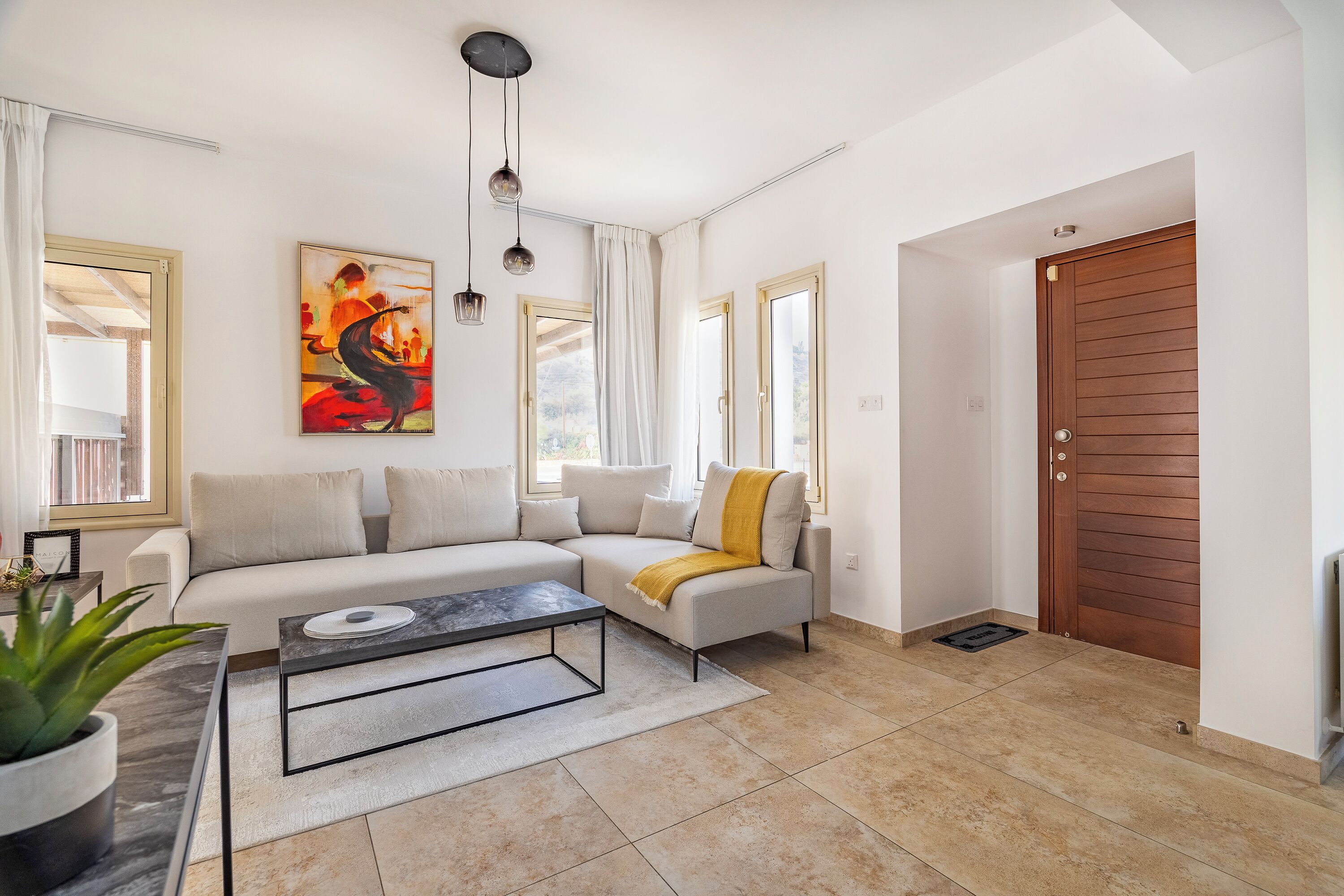 Un salon moderne avec un canapé d’angle, une table basse et un tableau accroché au mur.