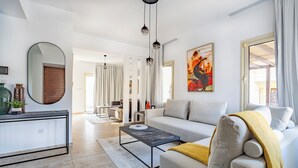 A modern living room with a sofa, coffee table, and a dining area in the background.