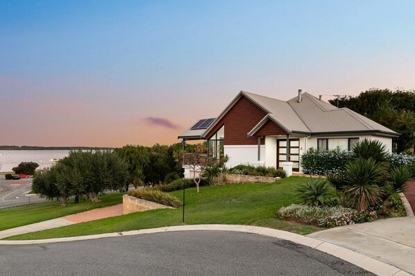 A modern house with a sloped roof, solar panels, and a well-maintained garden.