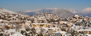 A snow-covered town with buildings clustered on a hillside, surrounded by mountains.