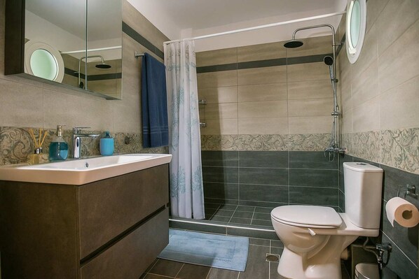 A modern bathroom with a shower, toilet, and sink.