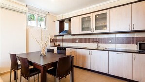 Une cuisine moderne avec une table et des chaises, des meubles de couleur claire et un dosseret carrelé.