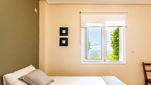 Une chambre avec un lit, une fenêtre donnant sur un beau paysage et un fauteuil.