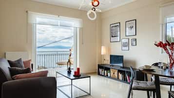 Relax in this open-plan living space with a sofa, dining table, and balcony offering a serene outdoor view.