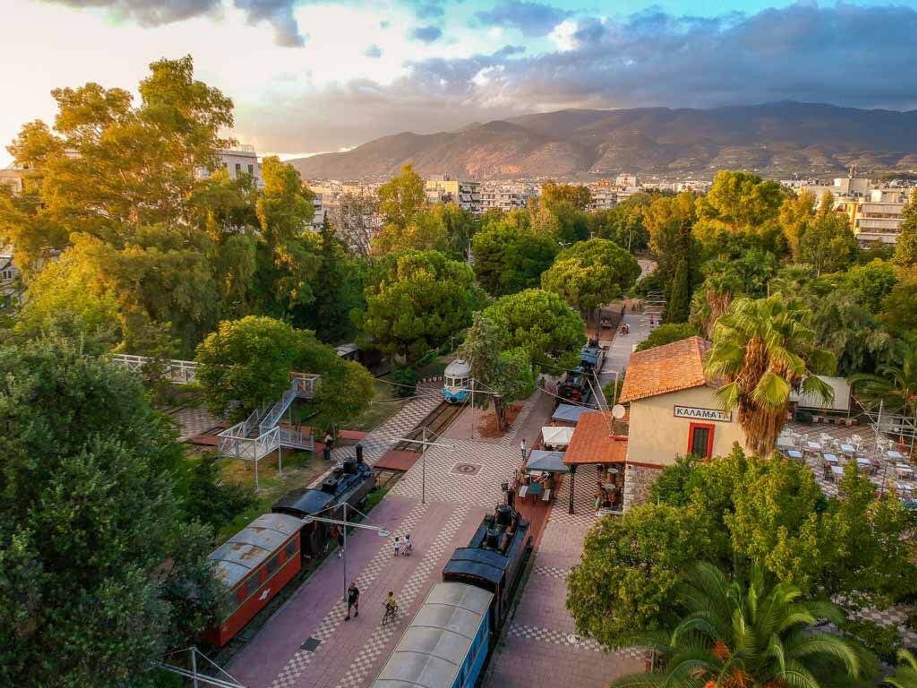 A train station with tracks, a small building labeled 'KARATEA', and surrounding greenery.