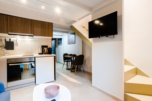 A modern kitchen with a built-in oven, a dining area with a table and chairs, and a staircase leading to another level. - Uncover Kalamata s Hidden Gem - Cosy City Nest (Kalamata)