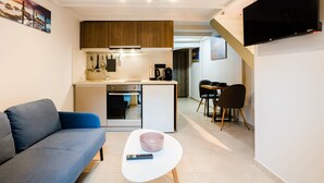 A compact living space with a kitchenette, a sofa, a coffee table, and a TV mounted on the wall. - Uncover Kalamata s Hidden Gem - Cosy City Nest (Kalamata)