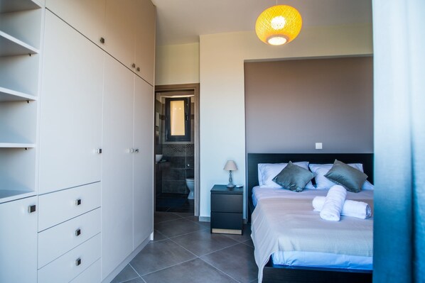 A bedroom with a bed, bedside table, lamp, and wardrobe. - Onar Zin Seabliss - Penelope Poolside Getaway (Xylokastro-Evrostina)