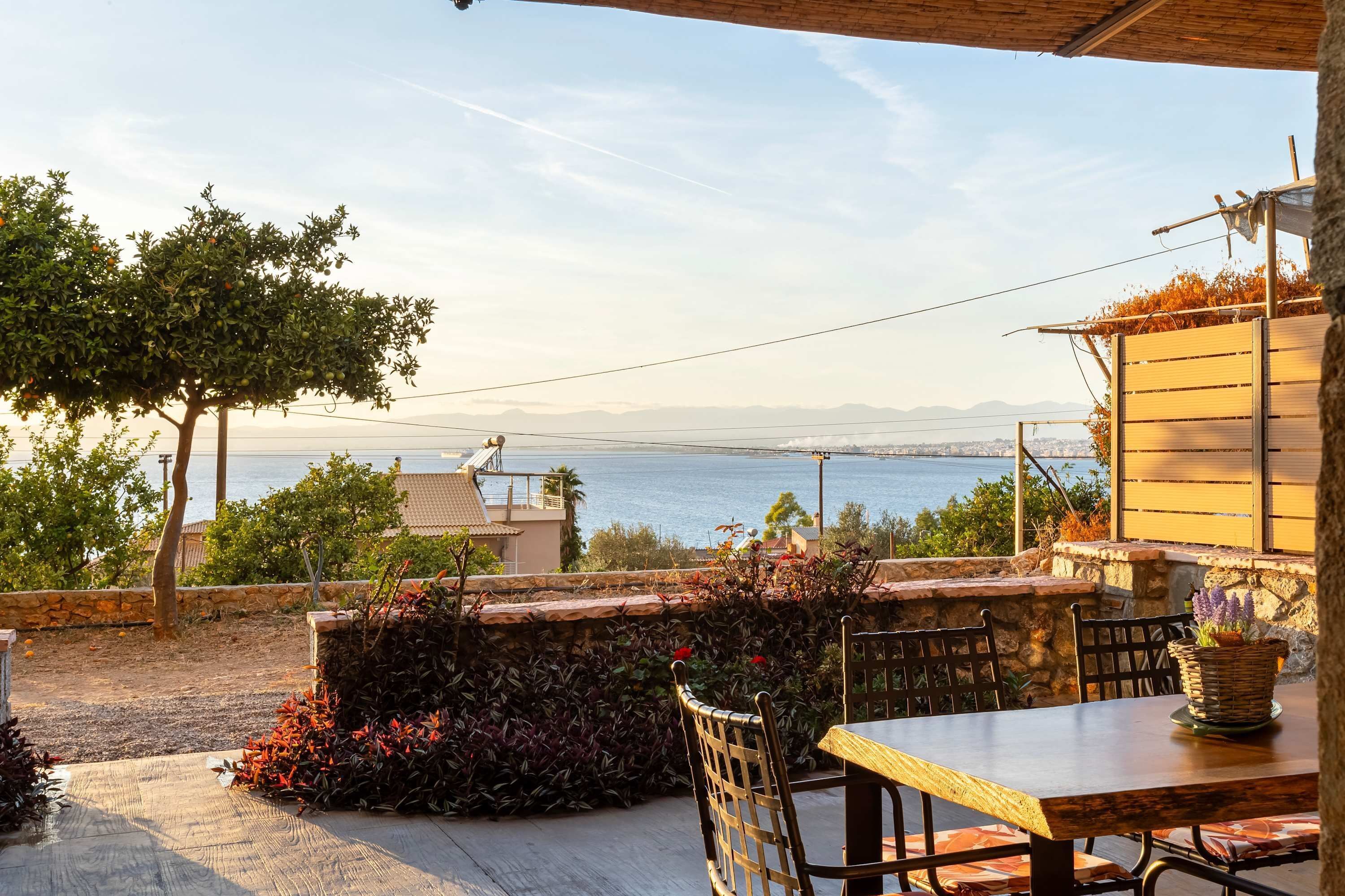 An outdoor patio with a table and chairs, overlooking a body of water and distant mountains.