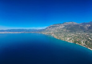 Un paysage côtier avec une mer bleue et limpide, une ville située le long de la côte et des montagnes en arrière-plan.
