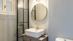 A bathroom with a white sink, a round mirror, and a toilet. - Estia Seaview Room - Ariadne Skopelos Getaway (Skopelos)