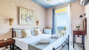 A hotel room with a bed, bedside table, and a view of the sea. - Estia Seaview Room - Ariadne Skopelos Getaway (Skopelos)