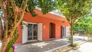 Un bâtiment à la façade rouge, doté de grandes portes vitrées et d’un chemin en pierre.