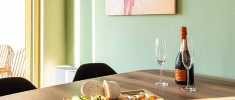 A wooden table with a cheese platter, two glasses, and a bottle of wine.