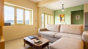 A living room with a sofa, a coffee table, and a painting on the wall. - Martinia Pool Escape - Tragos Panoramic Views (Kalamata)