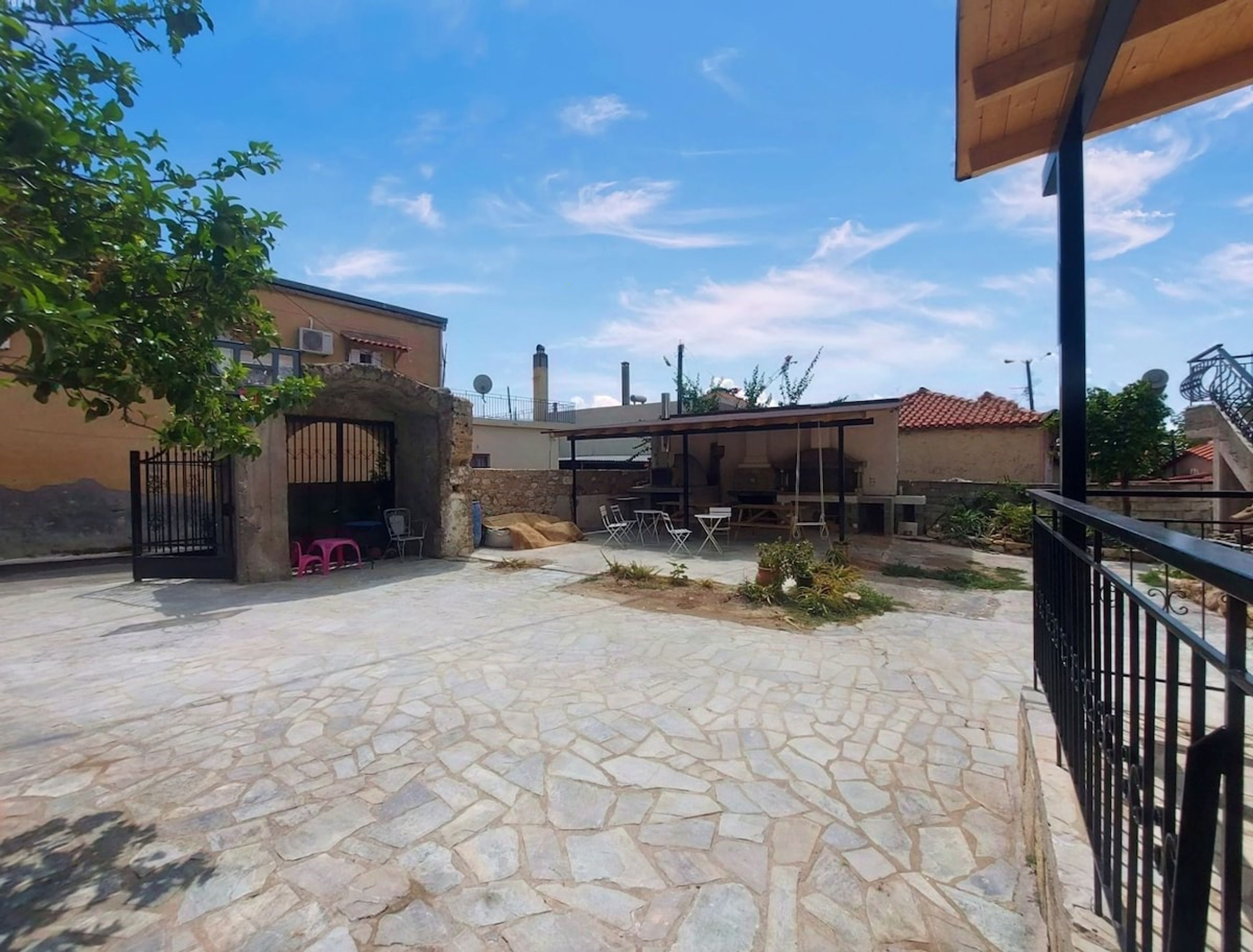 Un patio con suelo de piedra, mobiliario exterior y una zona de barbacoa cubierta.