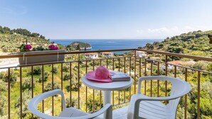 A balcony with white plastic chairs, a small round table, and a pink hat. - Persephone Seaview Room - Ariadne Skopelos Getaway (Skopelos)