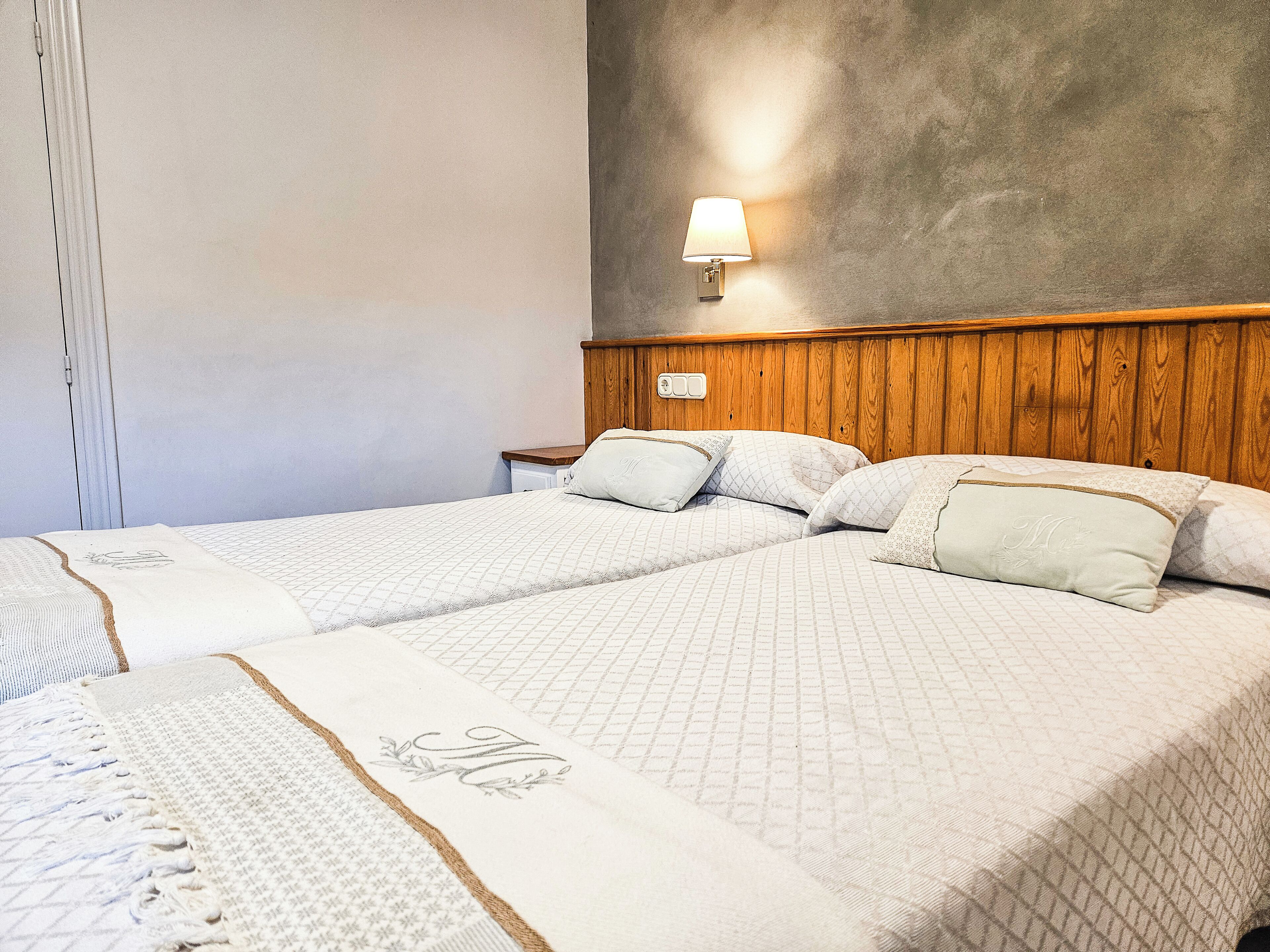 A double bed with a wooden headboard and a bedside table with a lamp.