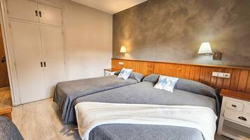 Un dormitorio con dos camas, cabeceros de madera, mesitas de noche y un armario.