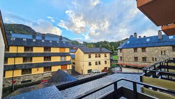 Blick auf eine Stadt mit Gebäuden mit Stein- und Holzfassaden, einem klaren Himmel und einer entfernten Bergkette.