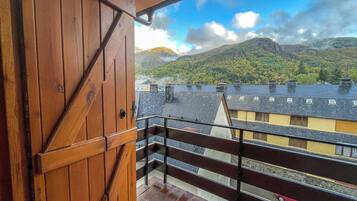A wooden door leading to a balcony with a view of a mountain and residential buildings.
