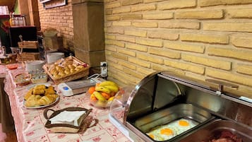 A buffet setup with various food items, including pastries, fruits, and cooked meats.