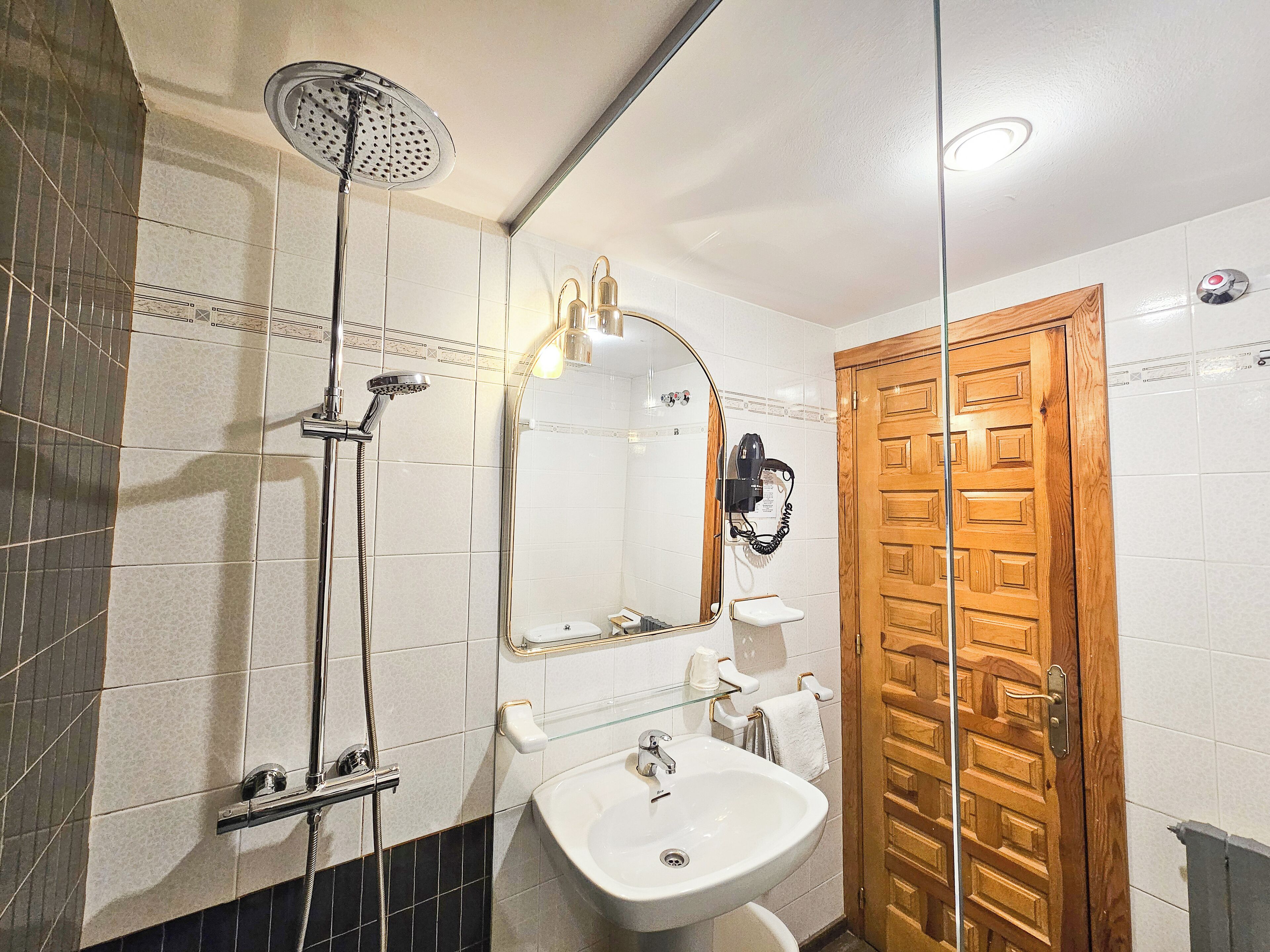 A bathroom with a shower, sink, and wooden door.