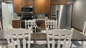 Una cocina moderna con armarios de madera, electrodomésticos de acero inoxidable y una mesa de comedor con sillas blancas.