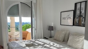 A bedroom with a large bed, a nightstand, a lamp, and a view of the outdoors. - 2-bed Sea View Apt, 10 Mins From Puerto Banus (Marbella)