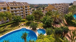 A residential area with multiple apartment buildings, a swimming pool, and lush greenery. - 2-bed Sea View Apt, 10 Mins From Puerto Banus (Marbella)
