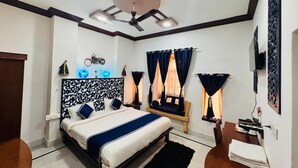 Un dormitorio moderno con una cama grande, un ventilador de techo y un televisor montado en la pared.