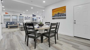 Un espace repas moderne avec une table ronde, des chaises foncées et un ventilateur de plafond.