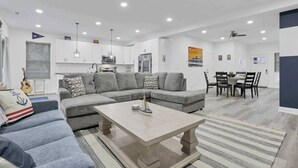Un salon moderne comprenant un canapé d’angle, une table basse et un coin repas avec une table et des chaises.