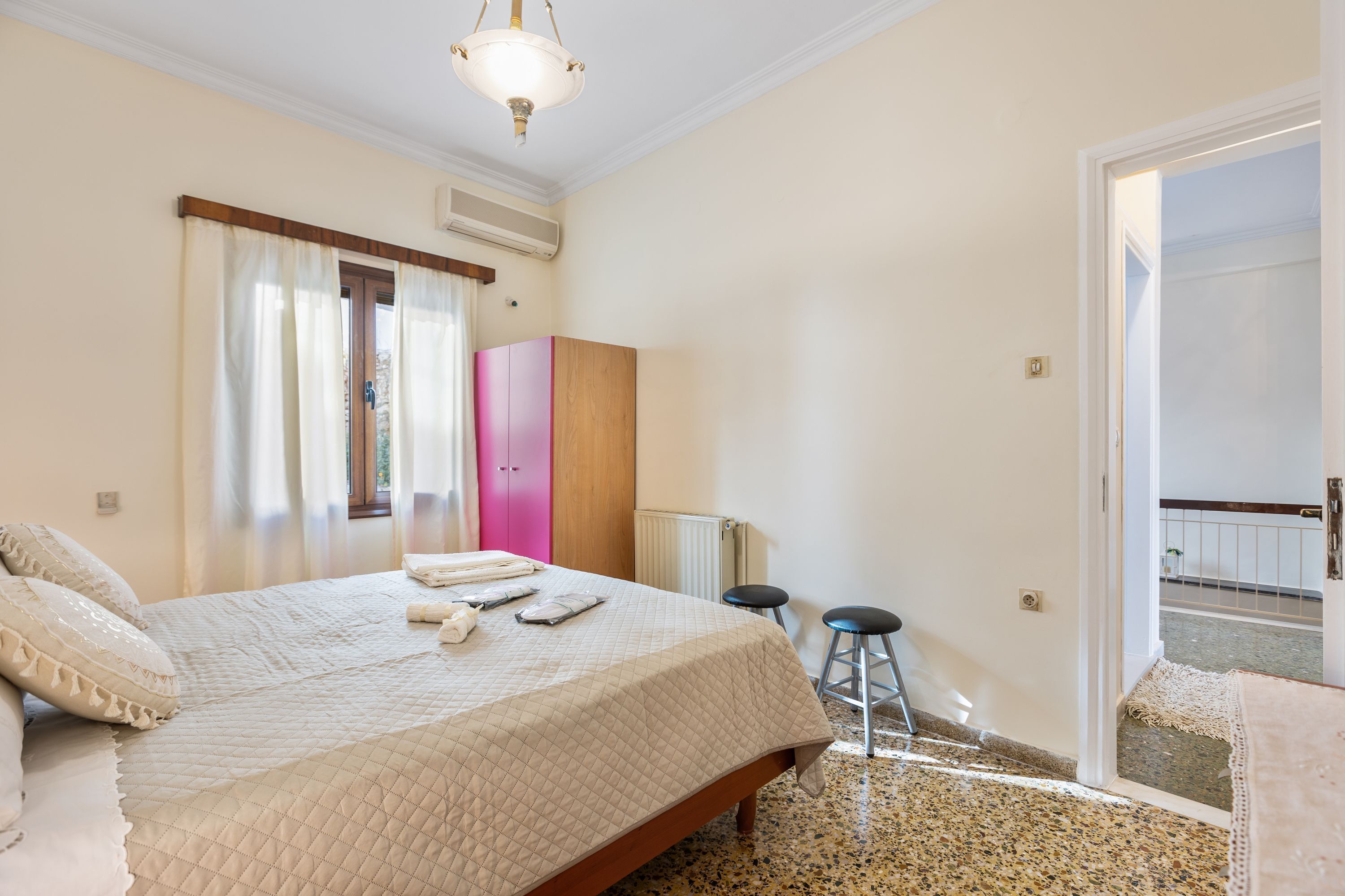 A bedroom with a bed, a wardrobe, a radiator, and a door leading to a balcony.
