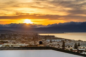 Une ville côtière offrant une vue sur la mer et les montagnes au coucher du soleil.