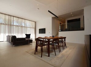 A modern living room with a dining area, large windows, and a staircase leading to an upper level. - Luxurious Sorici Villa With Private Pool and Mediterranean Landscape (Kanfanar)
