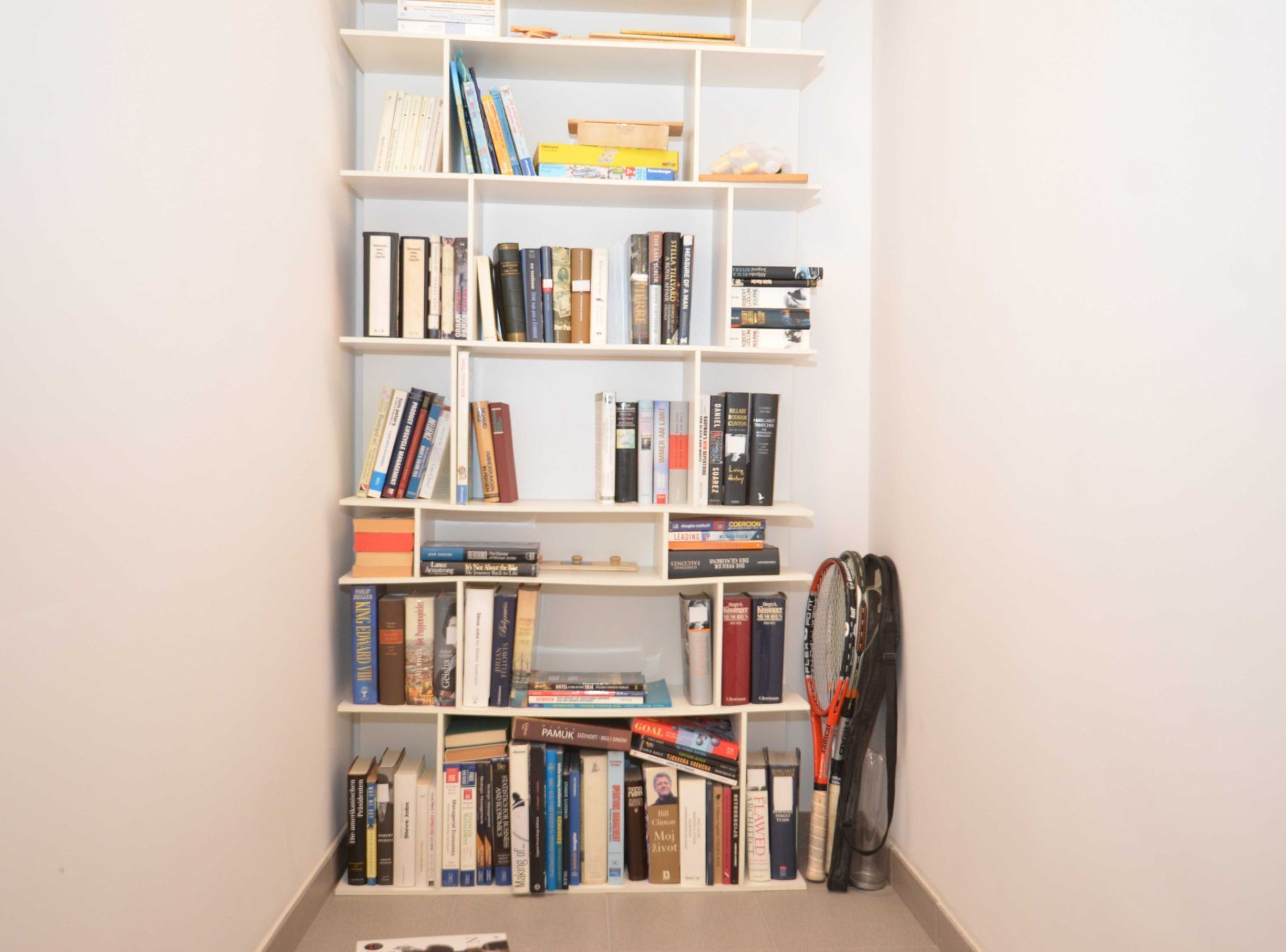 Uma estante com diversos livros e uma raquete de tênis.
