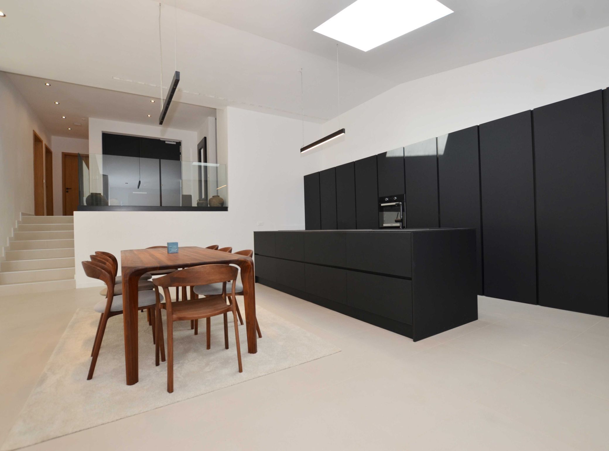 A modern kitchen with a black countertop, wooden dining table, and chairs.