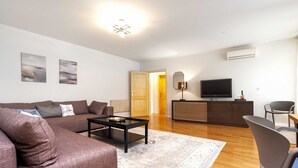 A modern living room with a brown sofa, a coffee table, and a TV on a wooden cabinet. - Charming Bright Gem Rovinj Downtown (Rovinj)