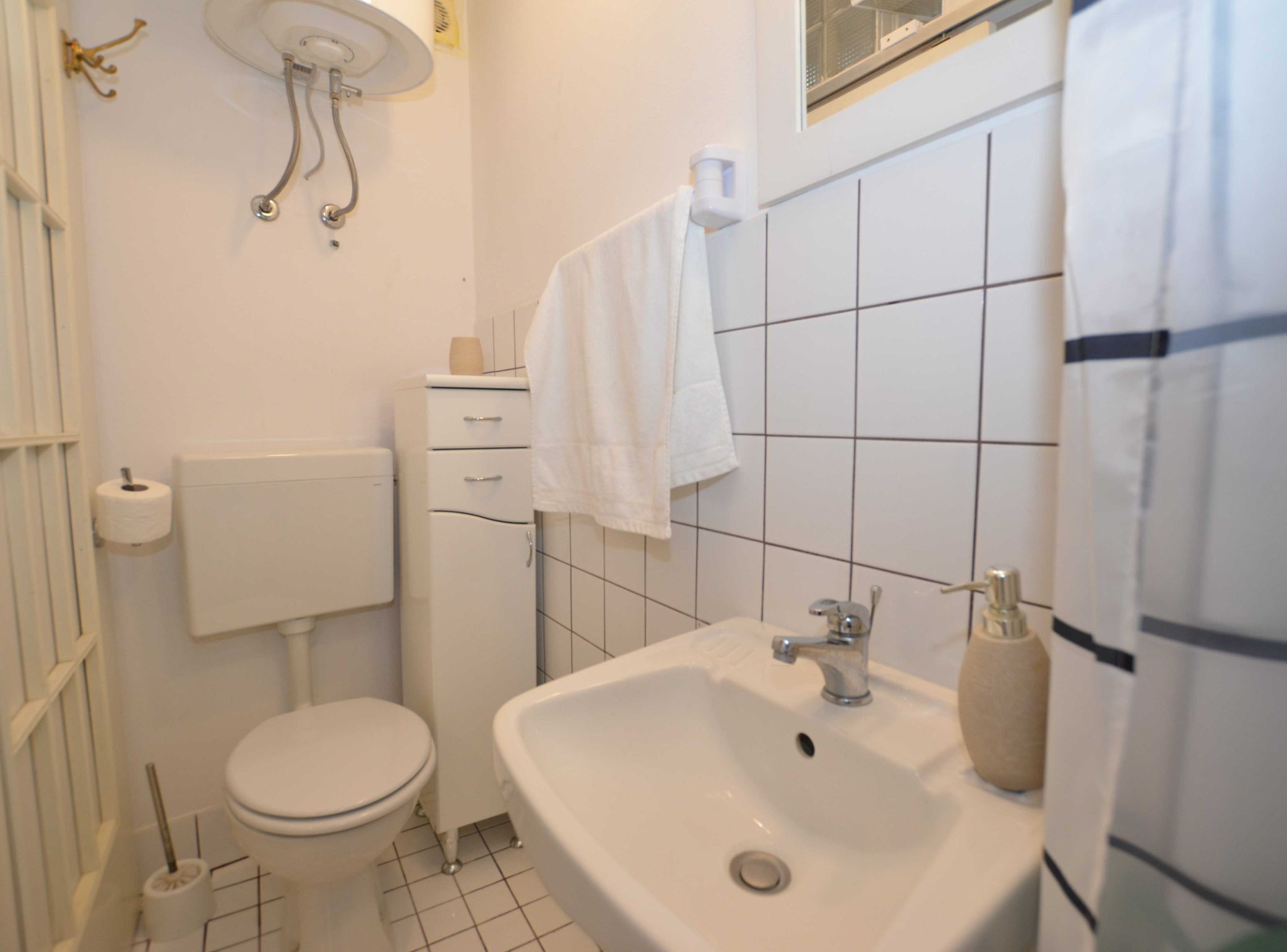 A bathroom with a toilet, sink, and towel hanging on the wall.