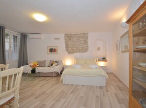 Ein Schlafzimmer mit einem Bett, einem Schlafsofa, einem Sessel und einem Essbereich mit einem Glastisch.