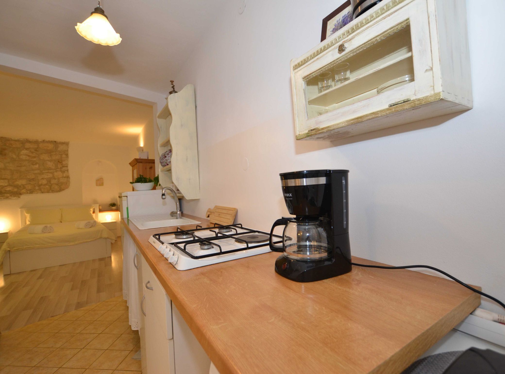 Una cocina compacta con estufa a gas, cafetera y un pequeño mueble sobre la encimera.